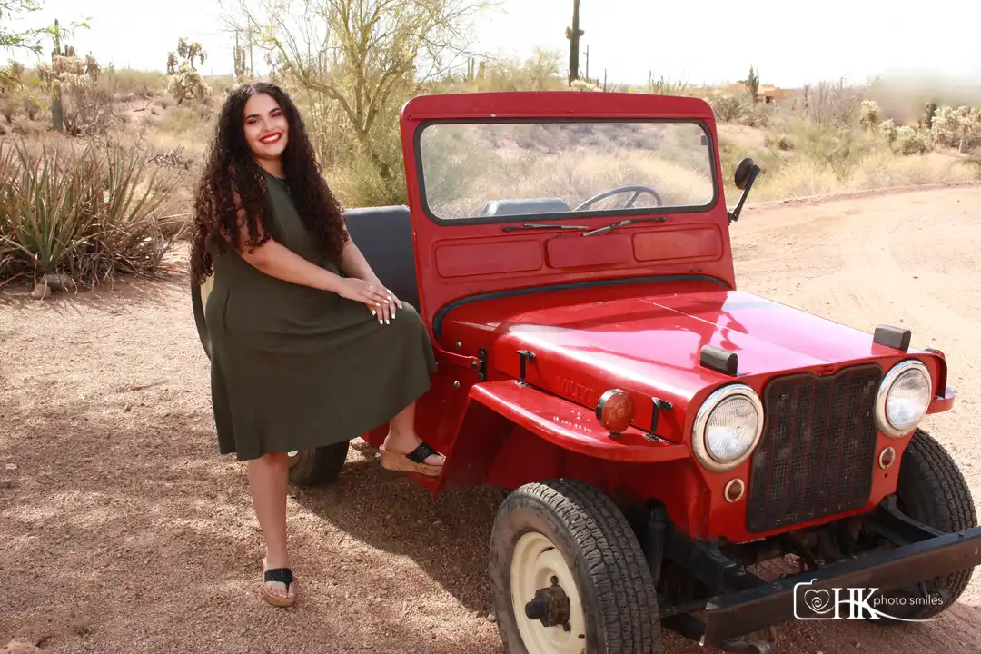High school female senior photo taken by her red hot jeep in green dress with desert background